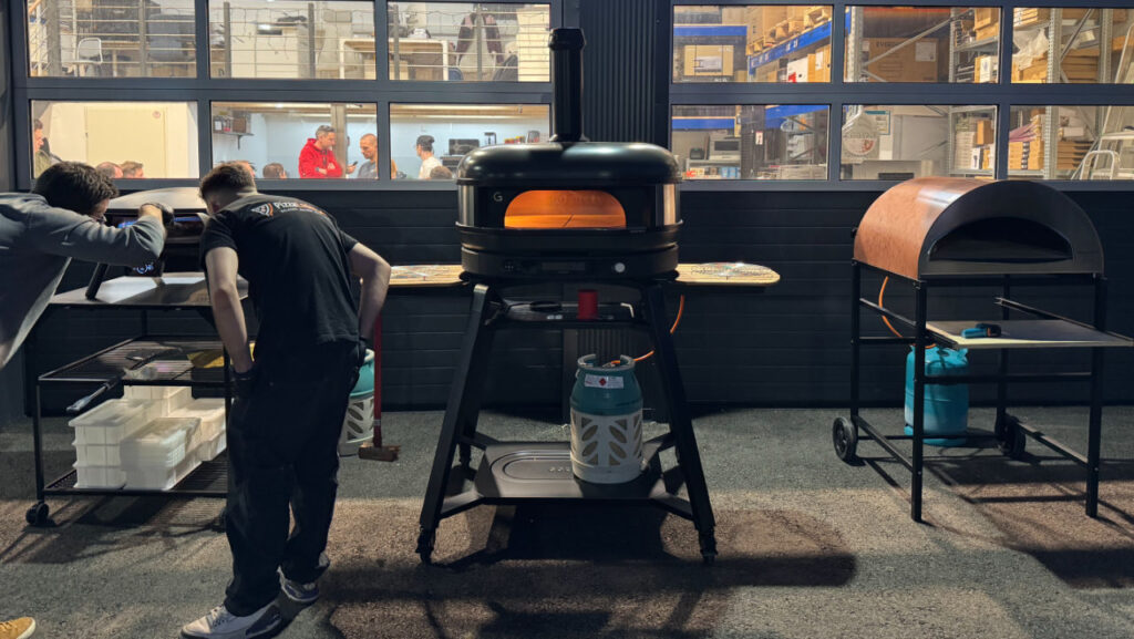 Teilnehmer beim Pizza-Workshop lernen den Umgang mit dem Pizzaofen