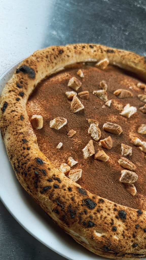 Tiramisu Pizza: Close-up Cornicione – Leoparding, Struktur, der Kontrast zur weißen Creme