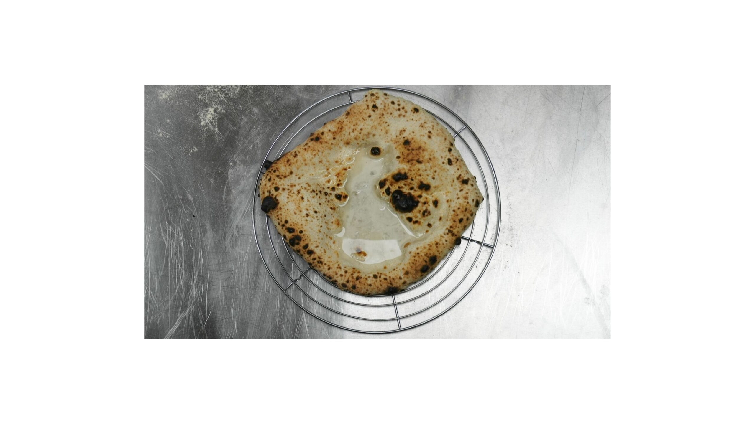 Pizzaboden nach der Eiswürfel-Methode – Wasserlache auf dem Teig sichtbar