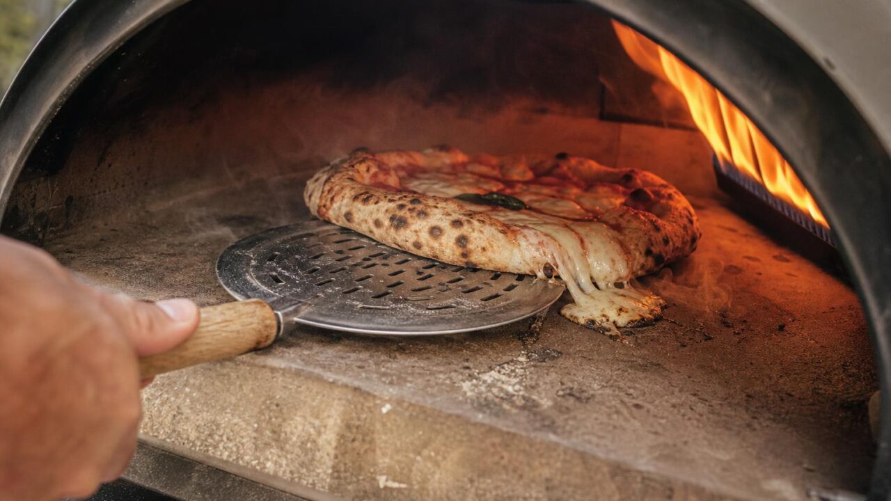 Pizzateig reißt beim Drehen im Gasofen, Käse rutscht auf den heißen Stein