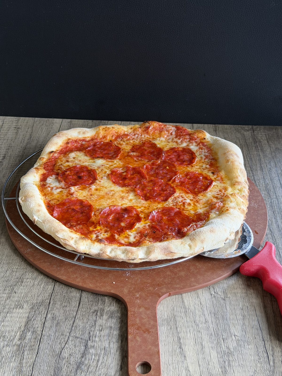 Pizza mit blassem Rand ohne Leopardenflecken auf dem Pizzaschieber