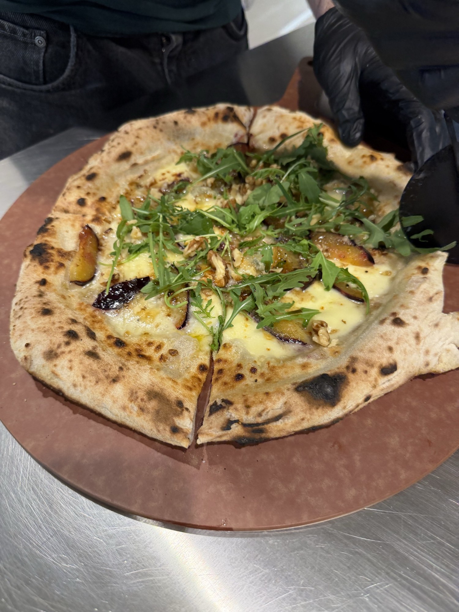 Angeschnittene Pizza Zwetschge Gorgonzola mit Rucola und Walnüssen, Nahaufnahme